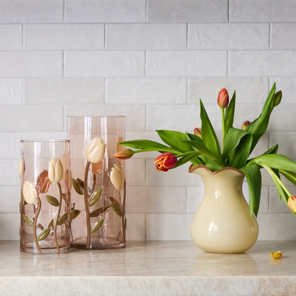 Decorative vases with floral designs on a countertop against a tiled wall.