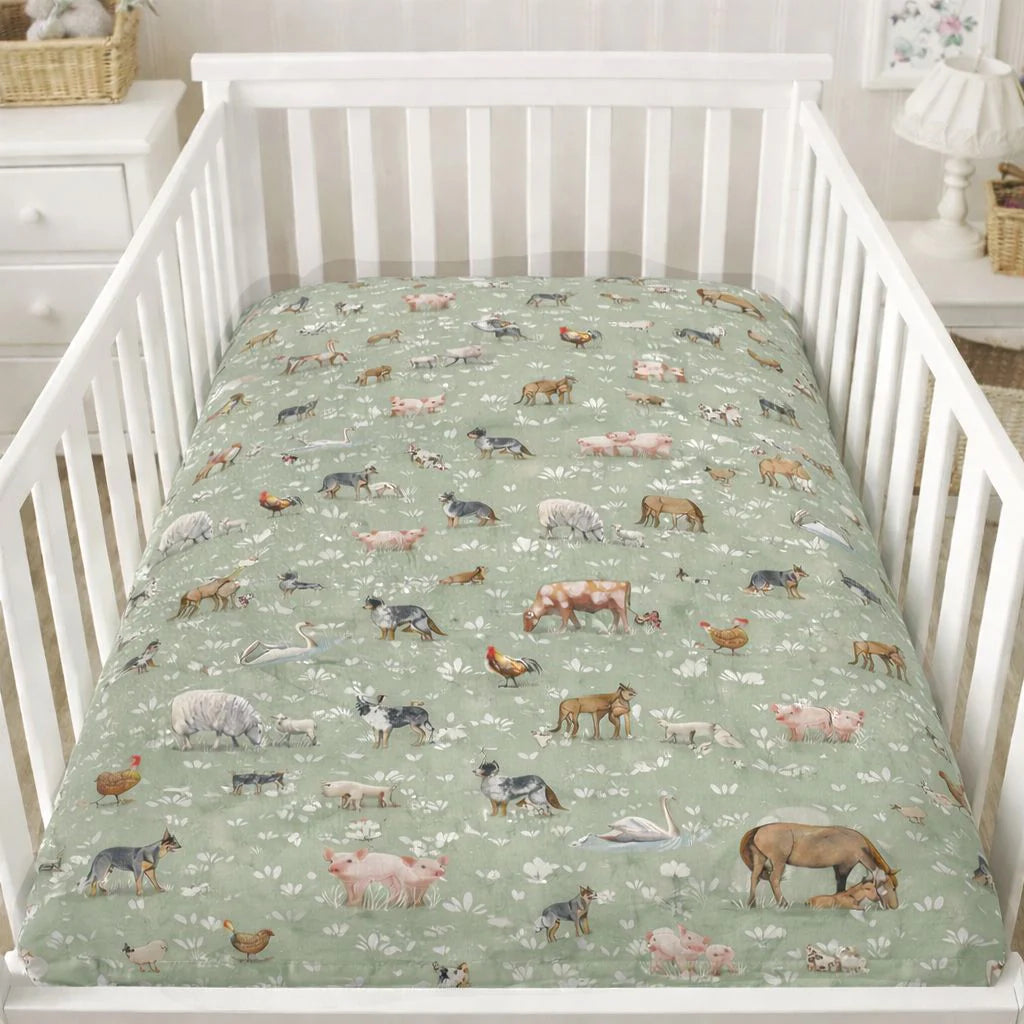 Crib with a green fitted sheet featuring animal illustrations in a nursery setting.