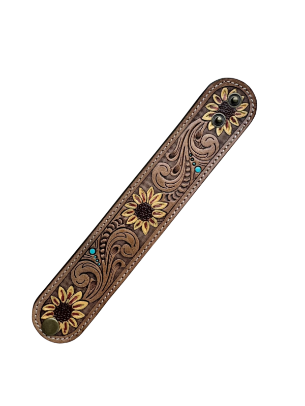 Sunflower Tooling Leather Wrist Band. Decorative wooden bar with sunflower designs and inlaid stones on a white background
