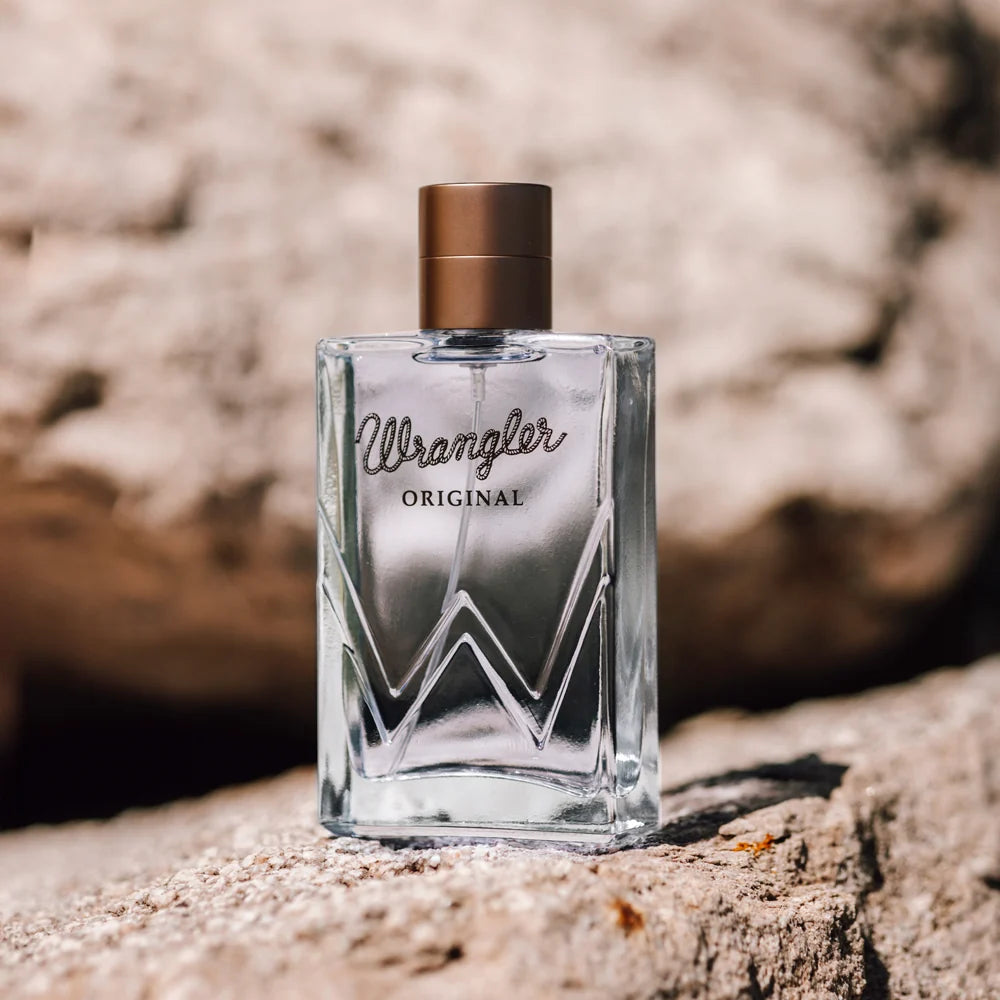 Clear perfume bottle labeled 'Wrangler Original' on a textured surface