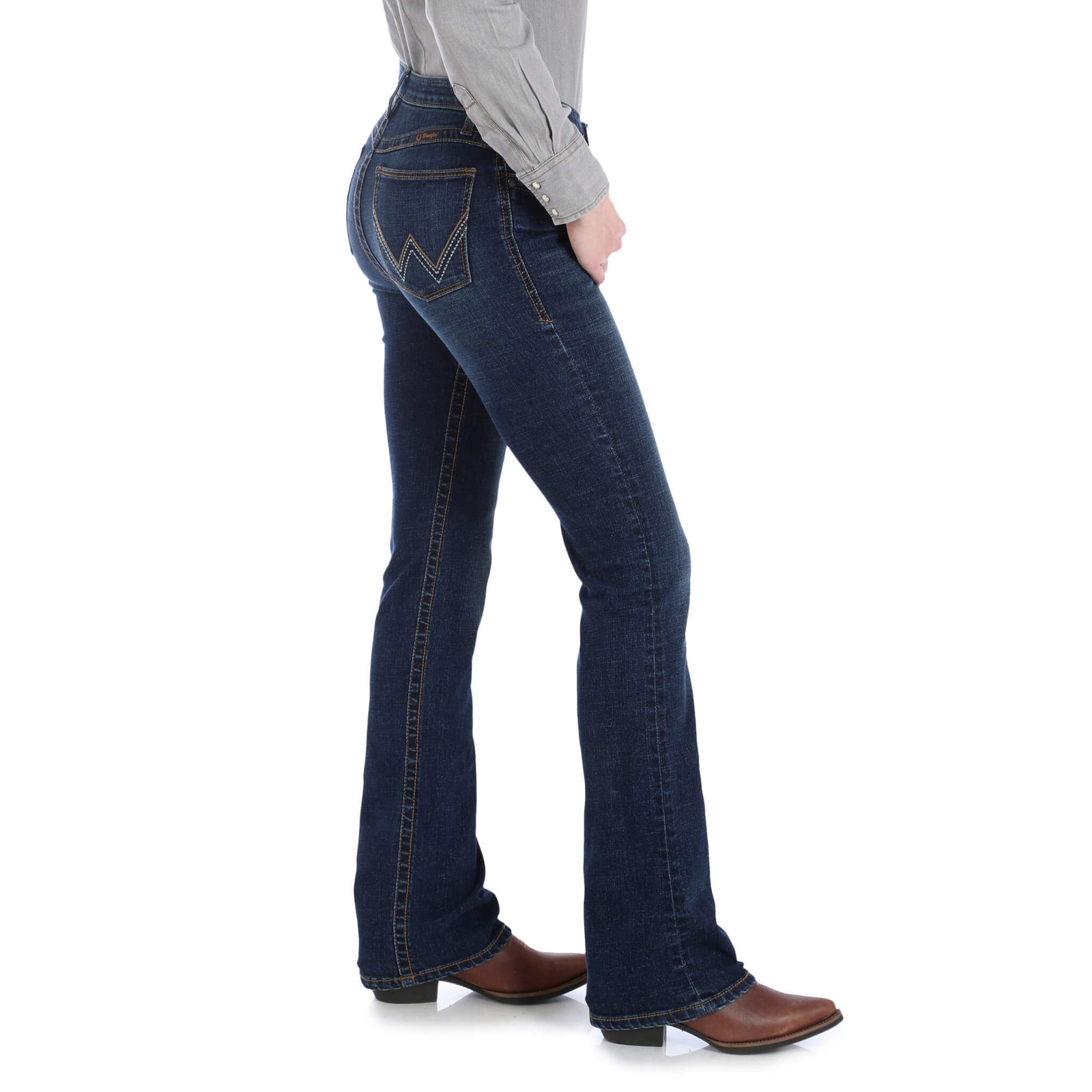A woman standing, wearing Wrangler Women's Willow Ultimate Riding Jeans with a high-rise waist and slim fit, in a medium wash denim.