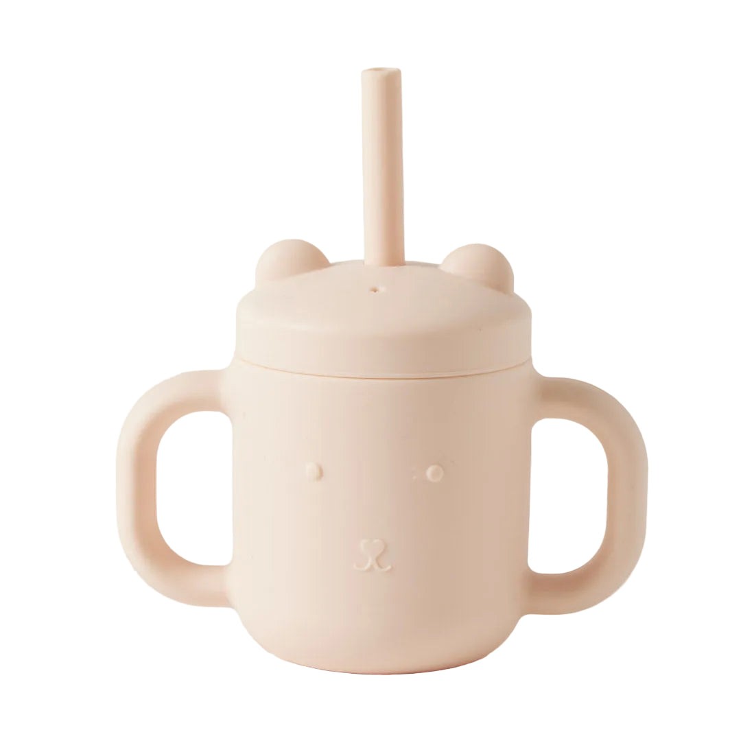 Pink sippy cup with a lid and handle on a light gray background