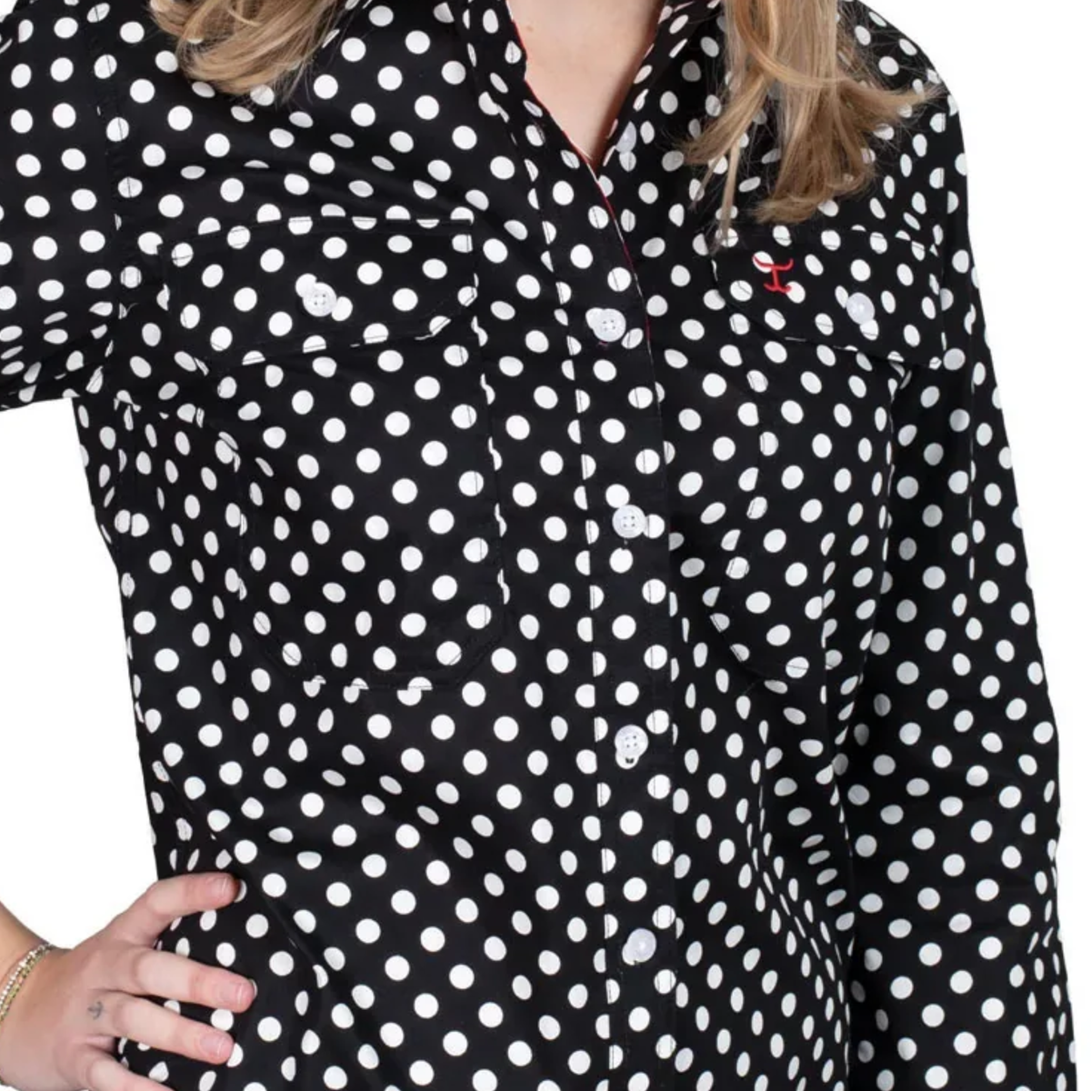 Black shirt with white polka dots worn by a person on a white background