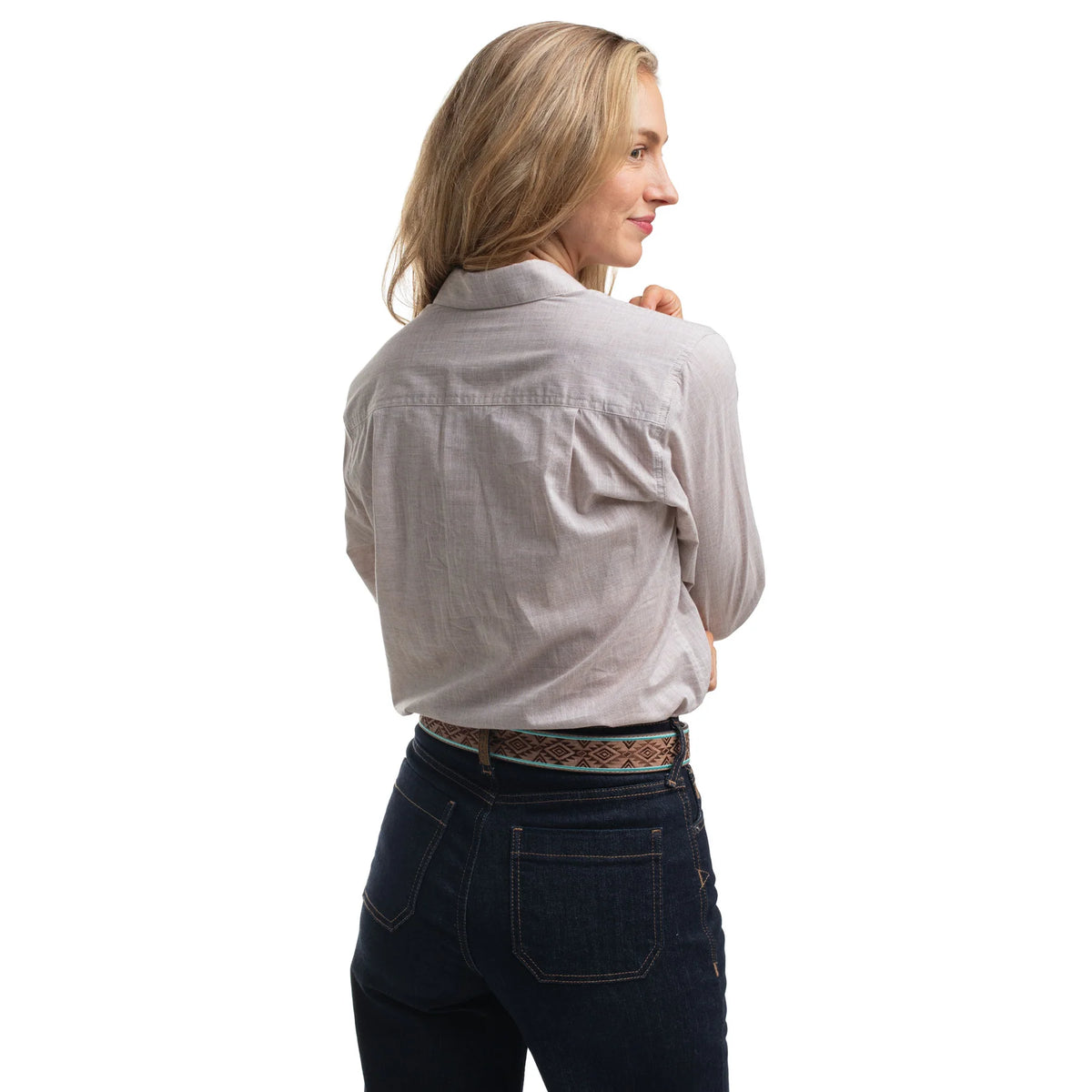 Woman wearing a light gray shirt and dark jeans on a white background