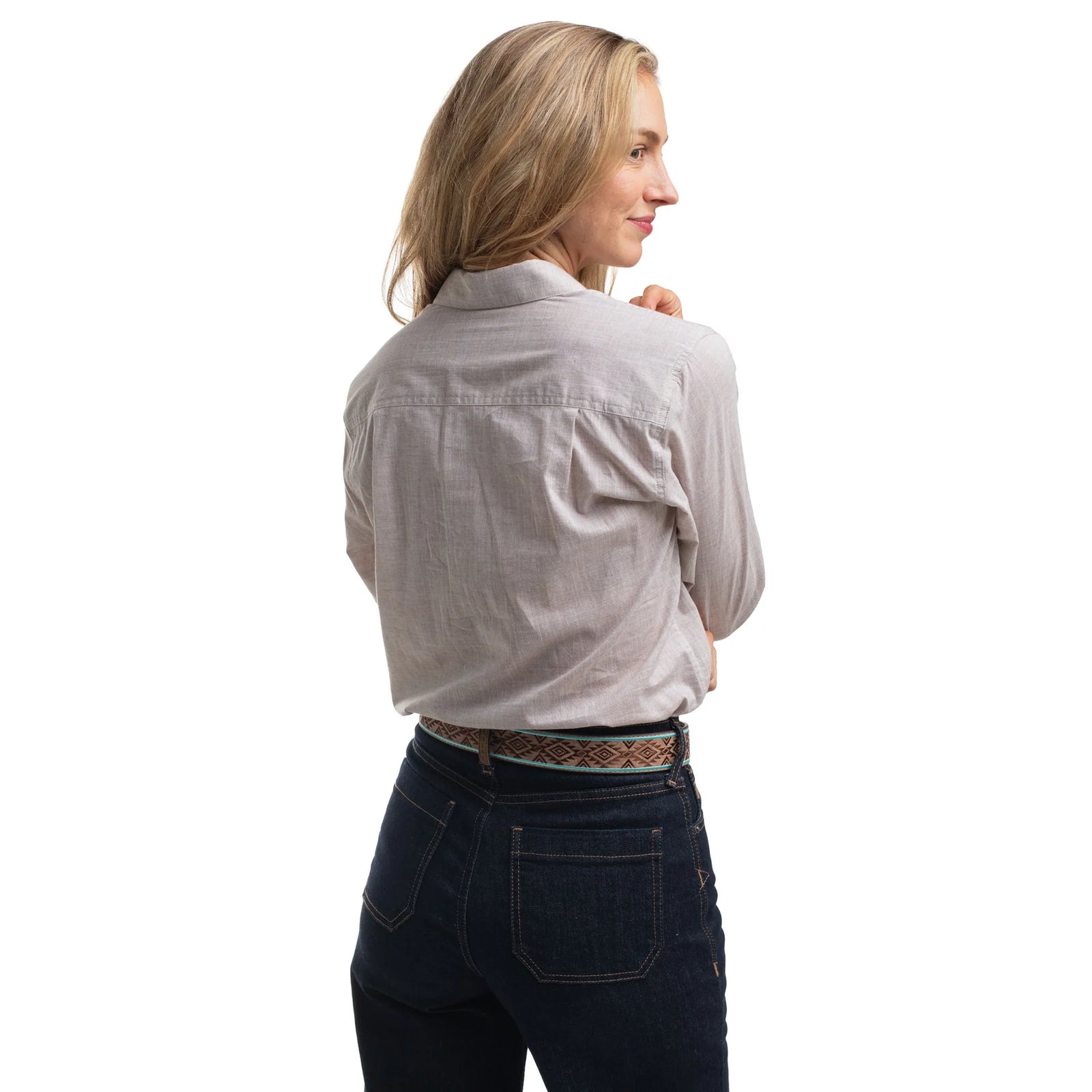Woman wearing a light gray shirt and dark jeans on a white background