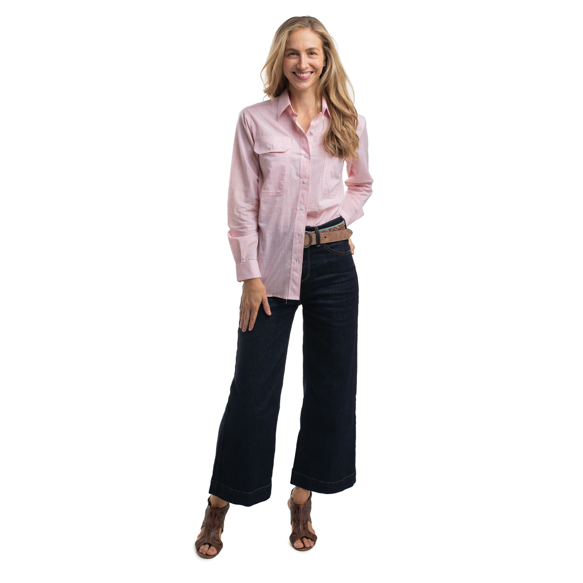 Woman wearing a pink shirt and dark jeans on a white background
