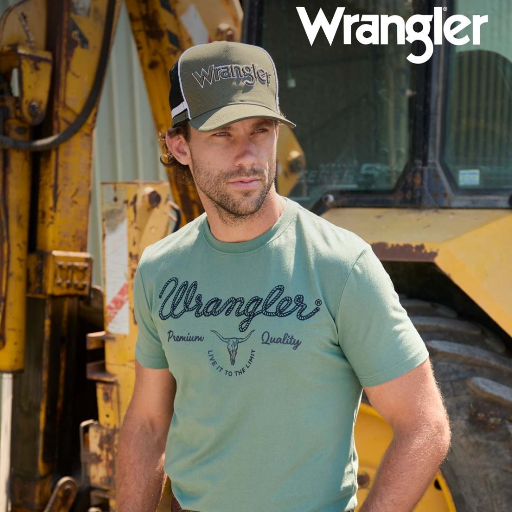 Wrangler Men's Arthur S/S T-Shirt. Man wearing a Wrangler t-shirt and cap in front of construction equipment
