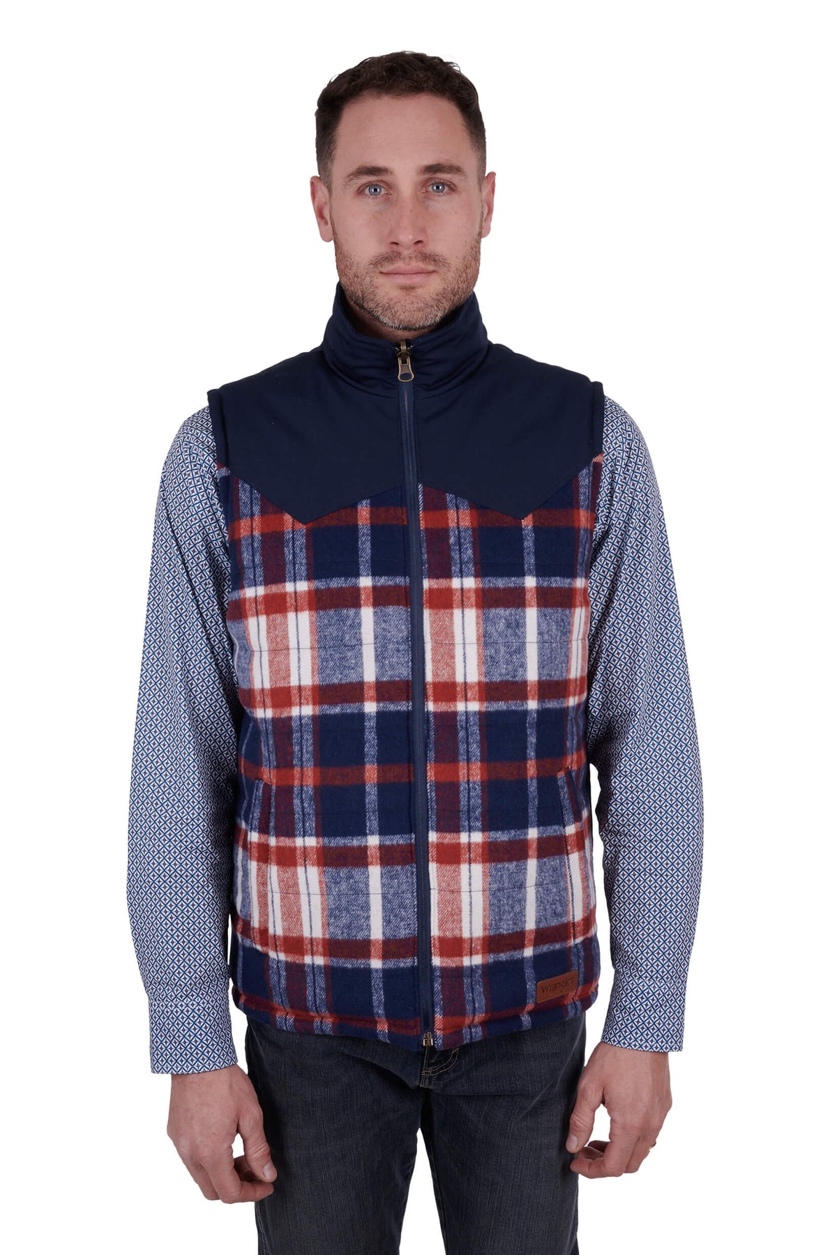 A man wearing a navy blue Wrangler reversible vest with a check pattern on the inside and a visible brand logo on the chest.