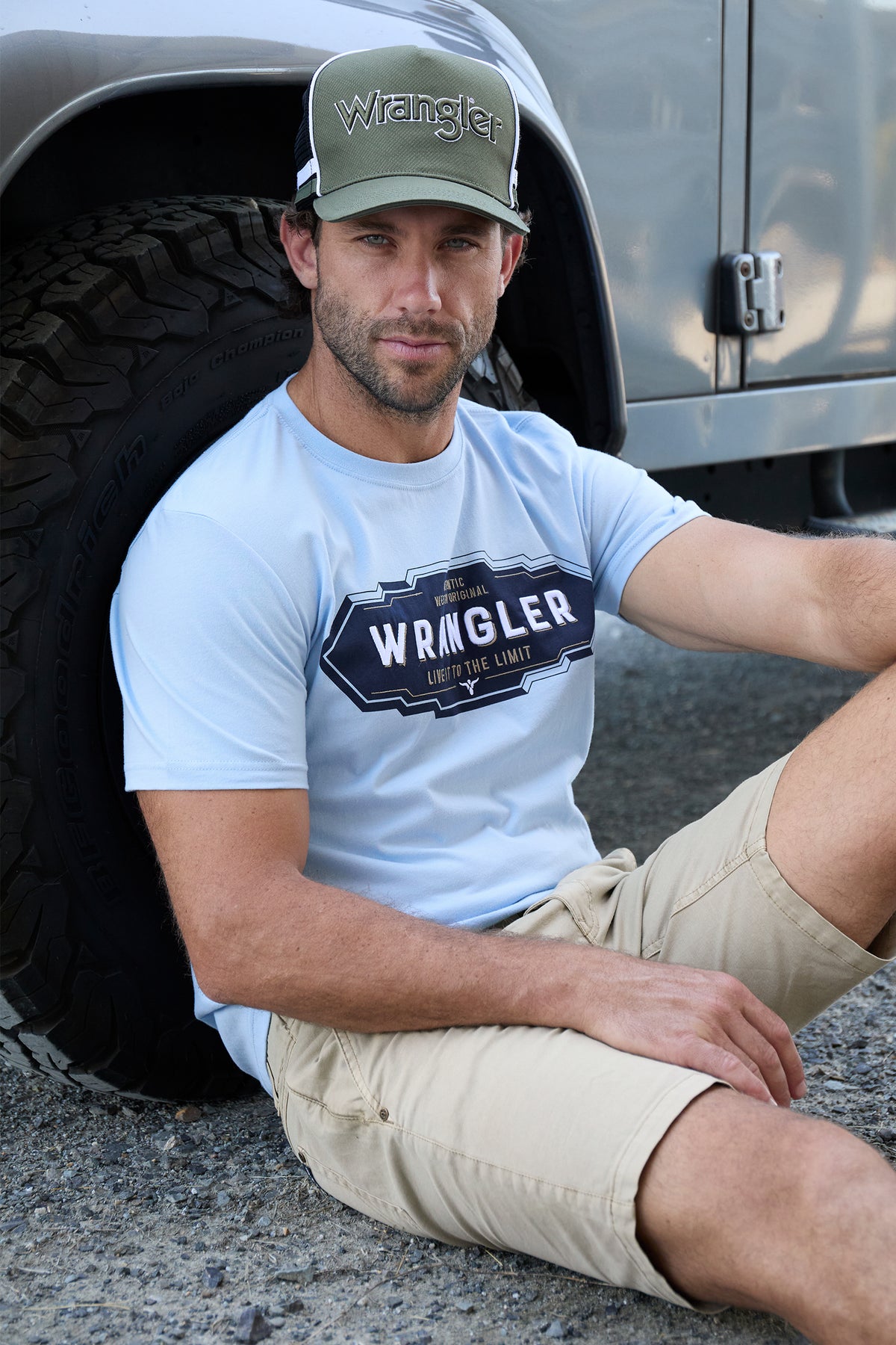 Wrangler Men's Roy S/S T-Shirt. Man wearing a Wrangler t-shirt and cap sitting next to a vehicle.
