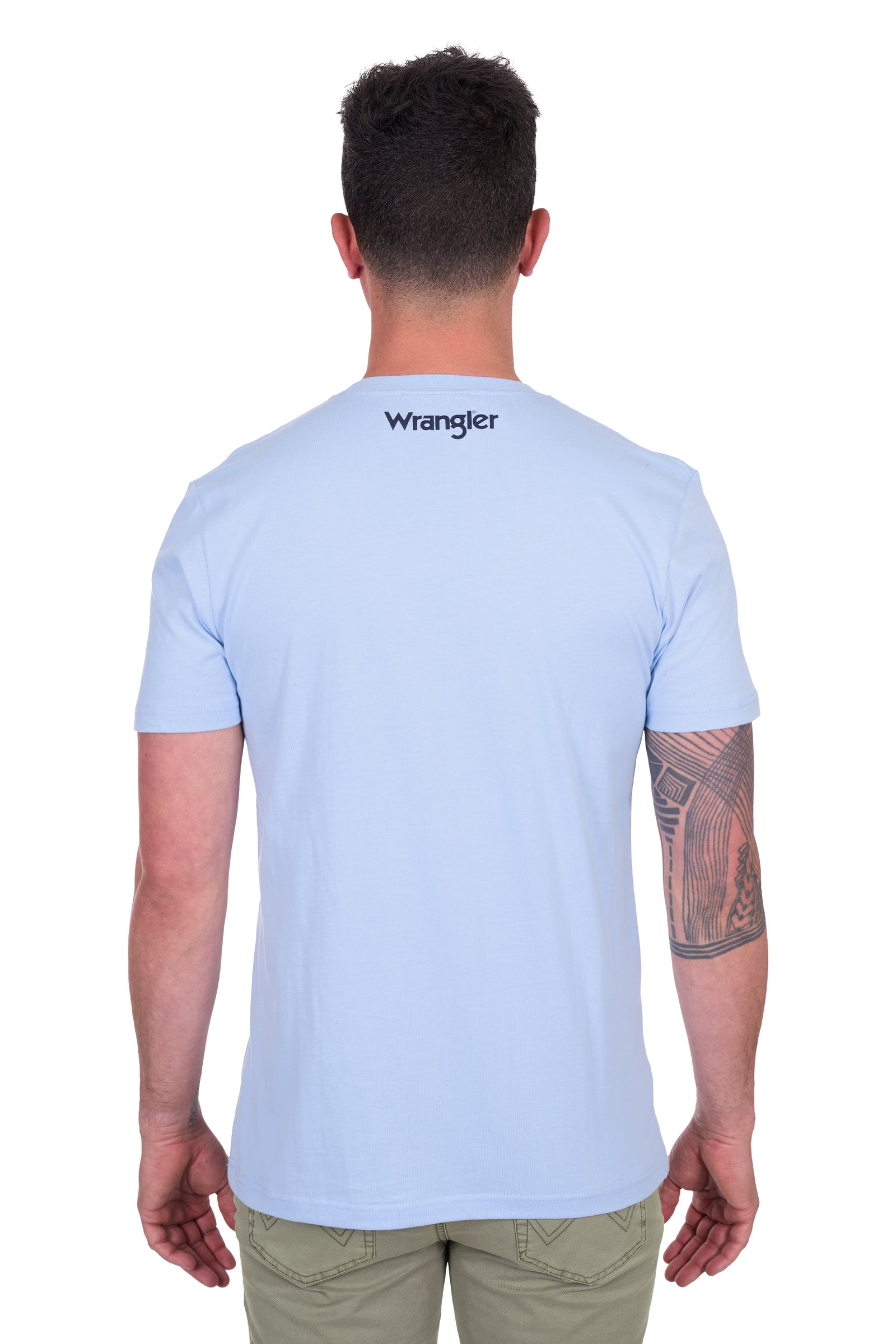 Wrangler Men's Roy S/S T-Shirt. Man wearing a light blue t-shirt with 'Wrangler' logo on the back, standing against a white background.