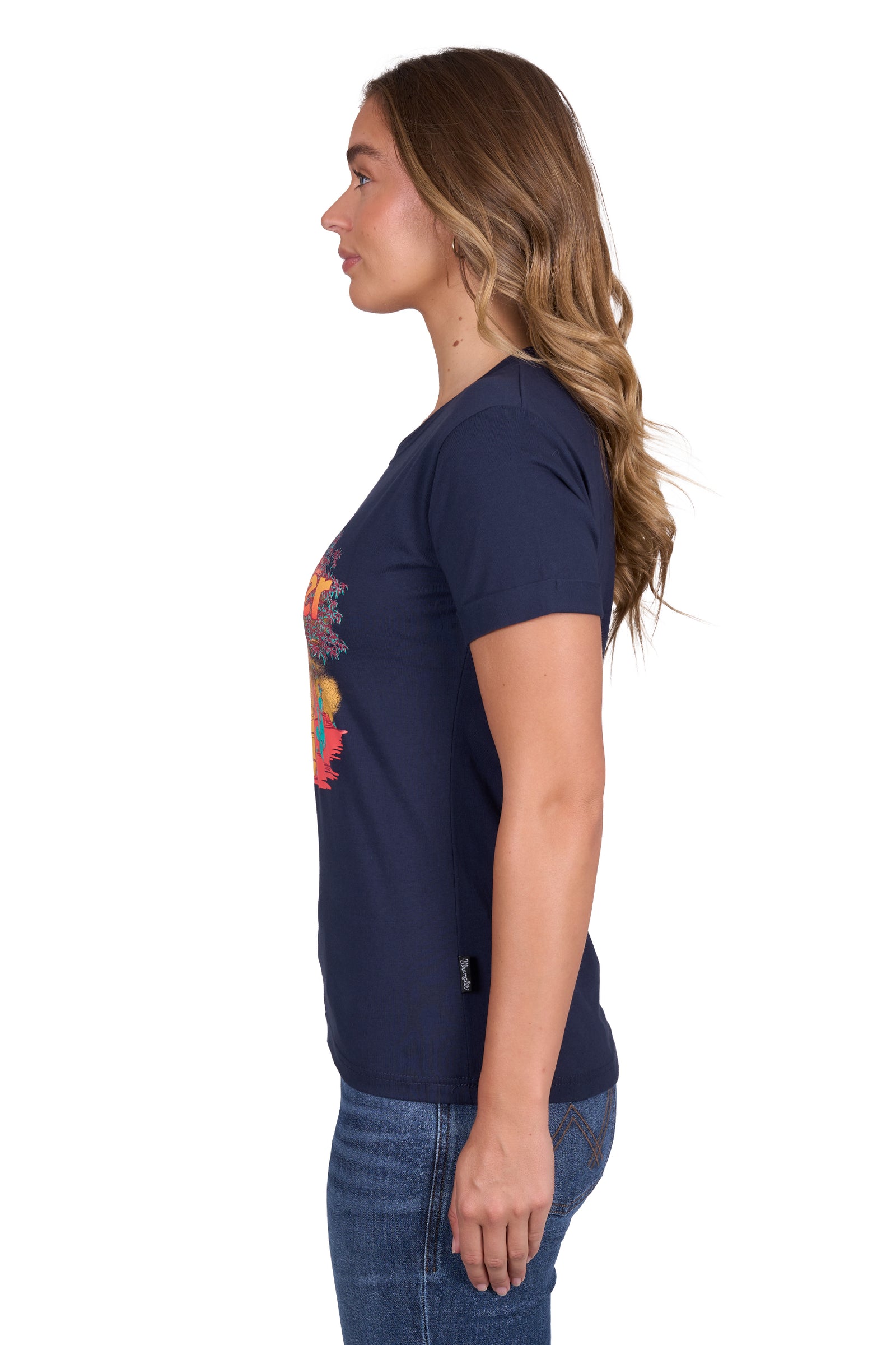 Wrangler Women's Lottie S/S T-Shirt. Person wearing a navy blue t-shirt with a colorful graphic design on a white background