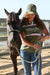 Wrangler Women's Piper HP Ponytail Trucker Cap. Woman in a Wrangler shirt standing next to a horse in an outdoor setting