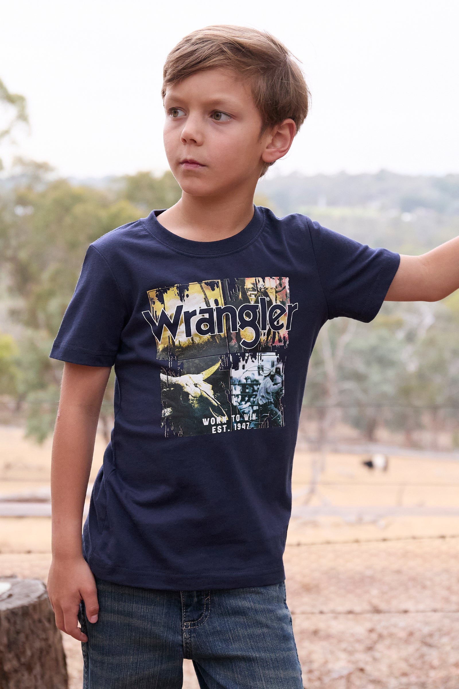 Wrangler Boy's Luis S/S T-Shirt. Child wearing a navy blue t-shirt with Wrangler logo outdoors