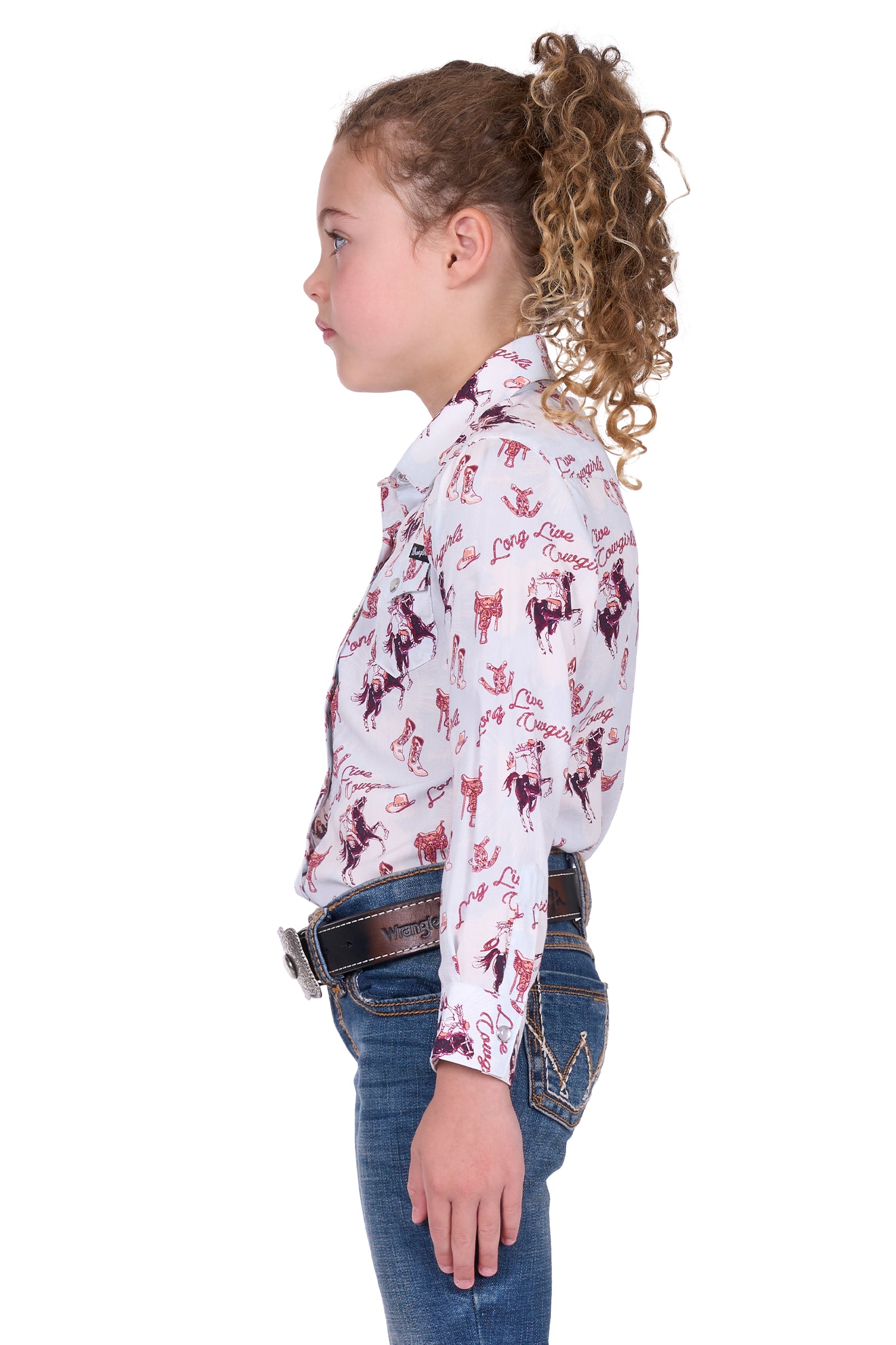 Wrangler Girl's Doreen L/S Western Shirt. Young girl wearing a long-sleeve shirt with horse print and jeans on a white background