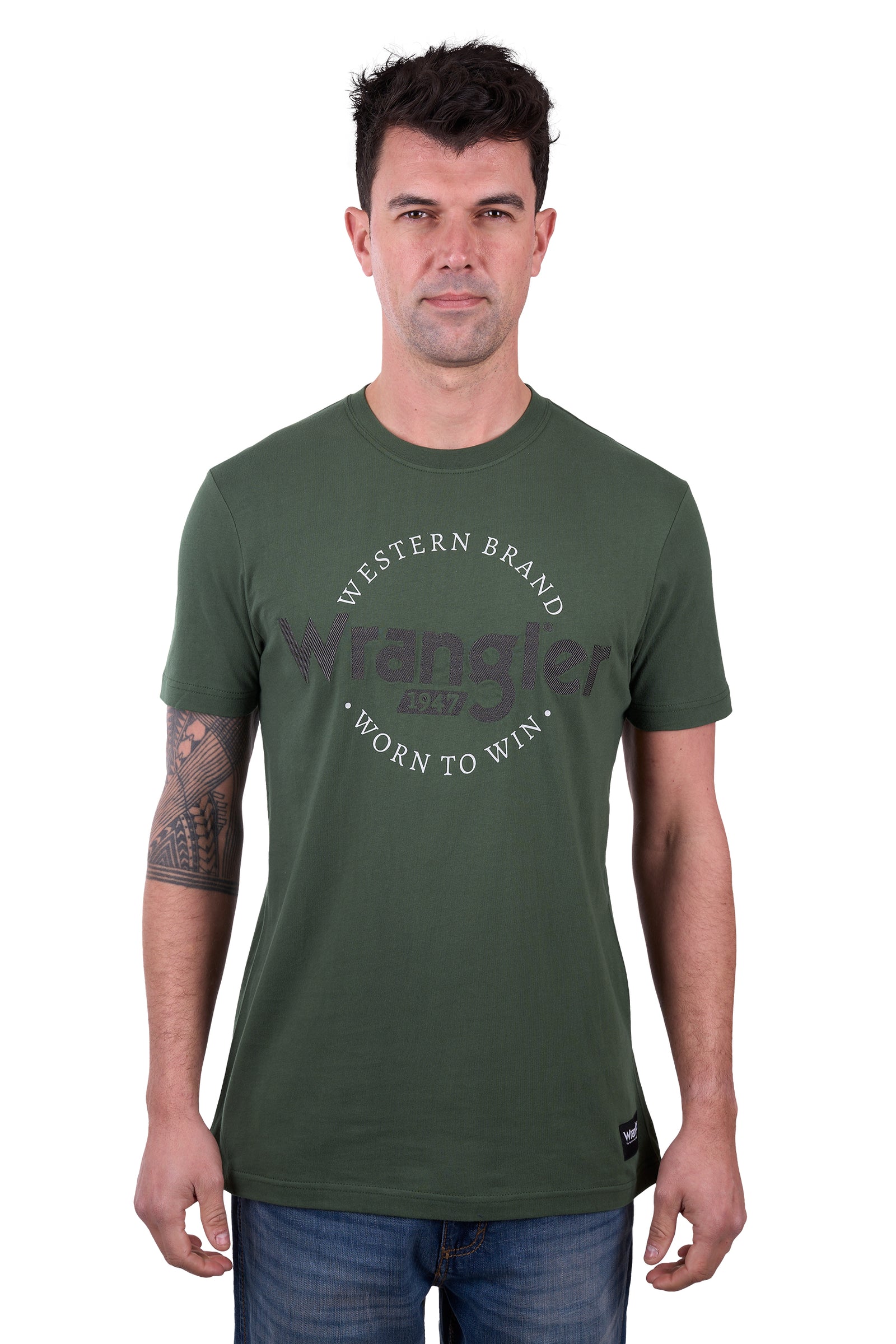 A man wearing a green short-sleeved Wrangler t-shirt with text on it, paired with blue jeans.