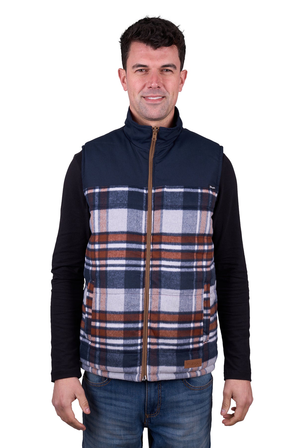 A man wearing a Wrangler Men's Koda Reversible Vest in navy and beige colors, paired with a black shirt and blue jeans.