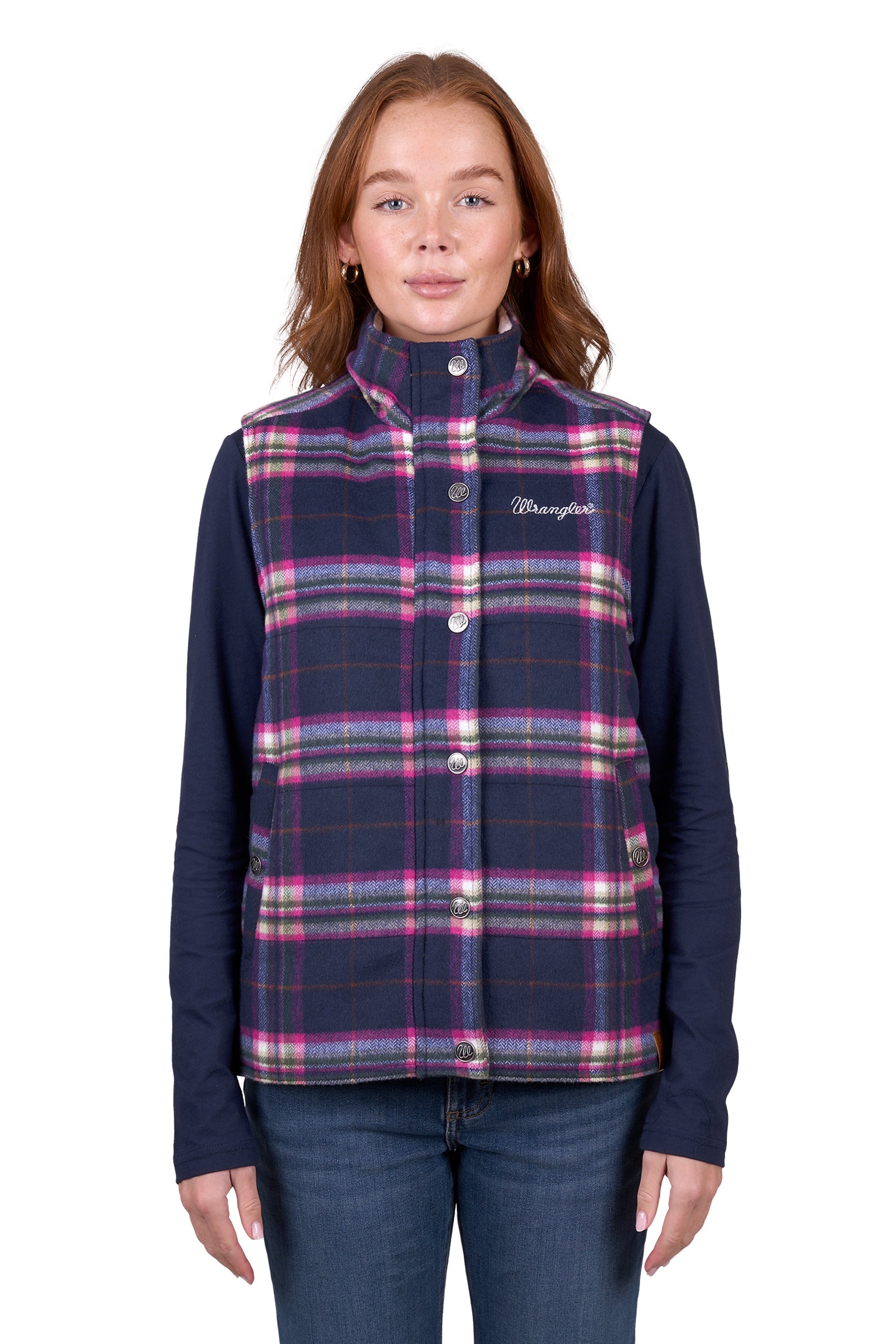 A woman wearing a purple and pink plaid vest with a sherpa collar, over a blue shirt, paired with jeans.