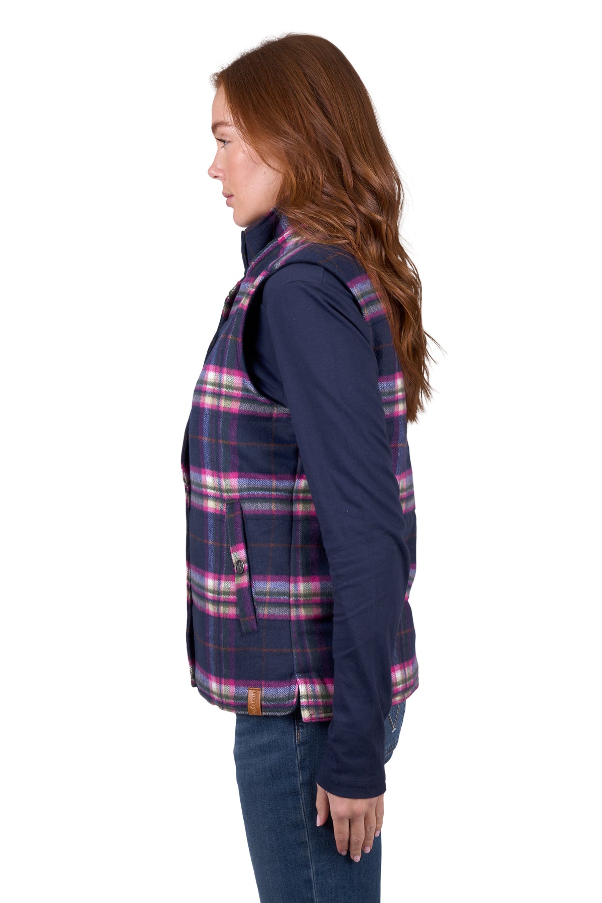 A woman wearing a purple and pink plaid vest with a sherpa collar, over a blue shirt, paired with jeans.