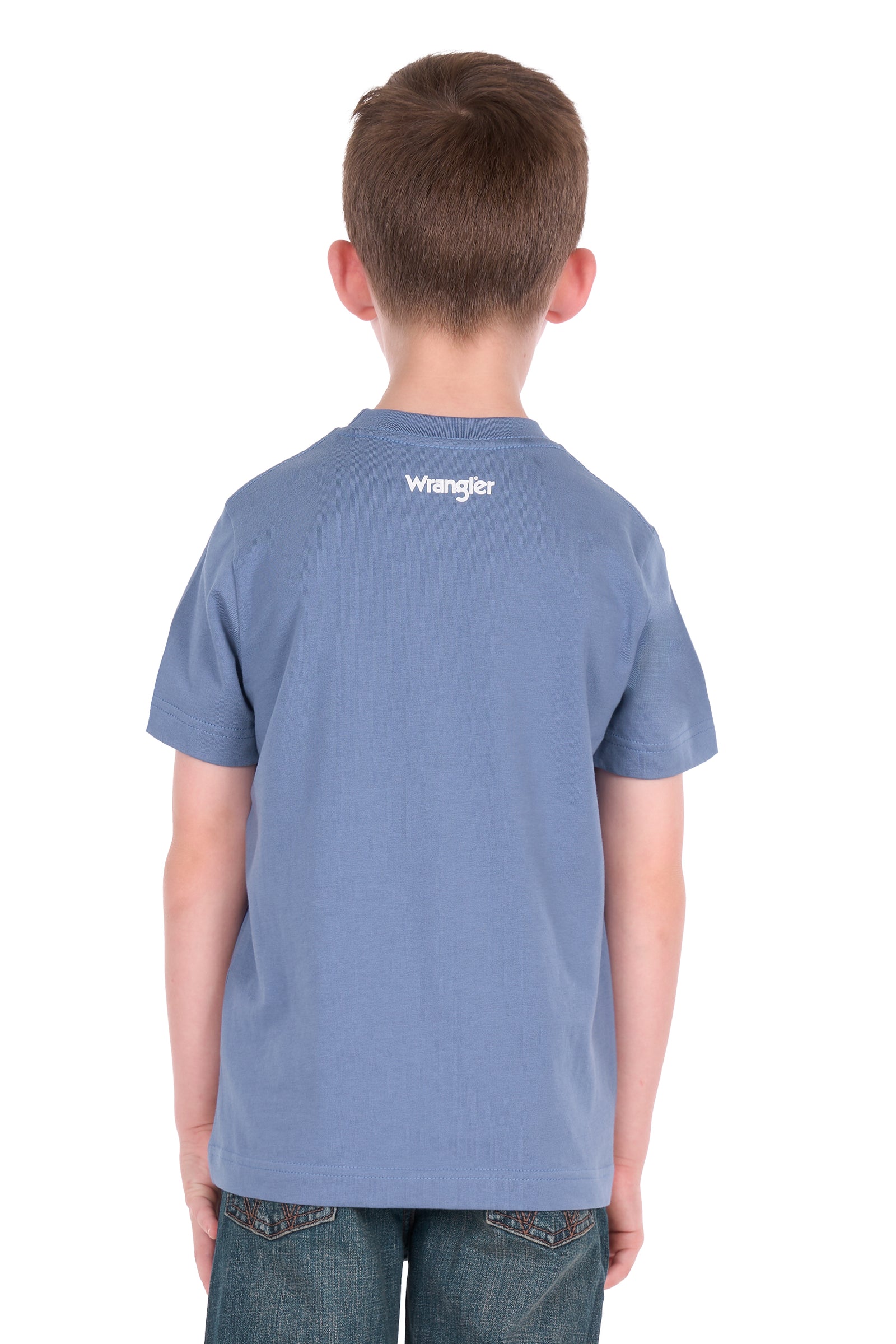 A young boy wearing a blue Wrangler t-shirt with a cowboy graphic and jeans, standing against a plain white background.