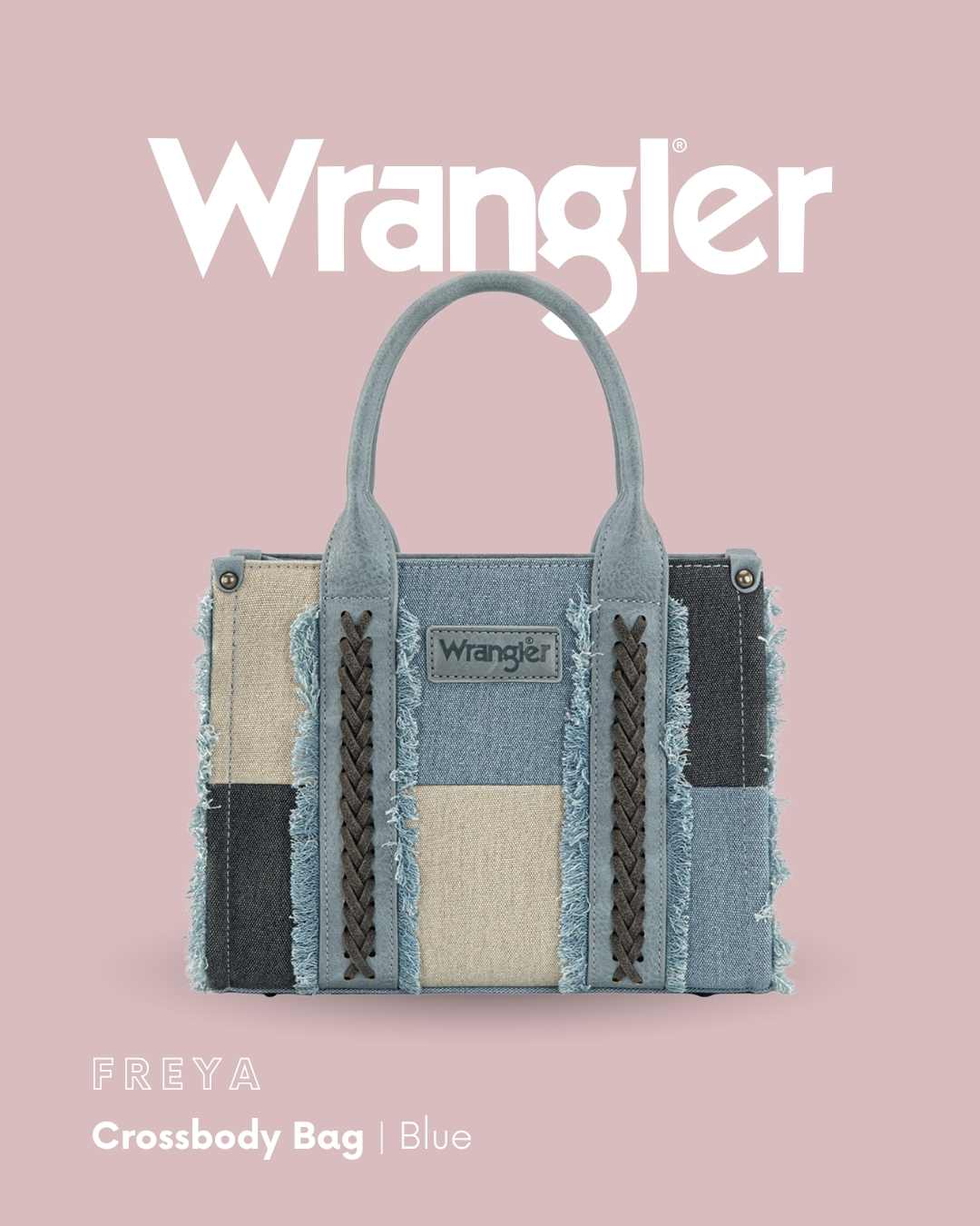 Wrangler Freya Crossbody Bag in blue denim patchwork with beige, black, and gray panels, braided details, and frayed edges, shown on a dusty pink background with the Wrangler logo and product name.