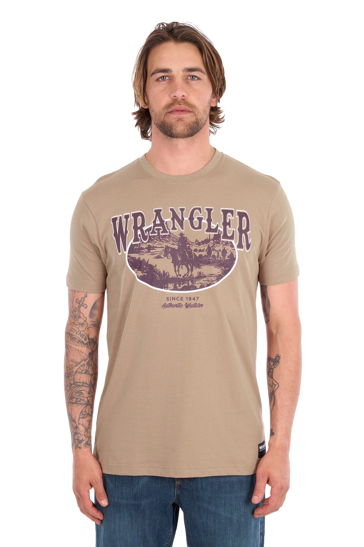 A man wearing a tan Wrangler short-sleeve t-shirt with a vintage-style circular graphic on the chest, paired with blue jeans, photographed against a plain white background.