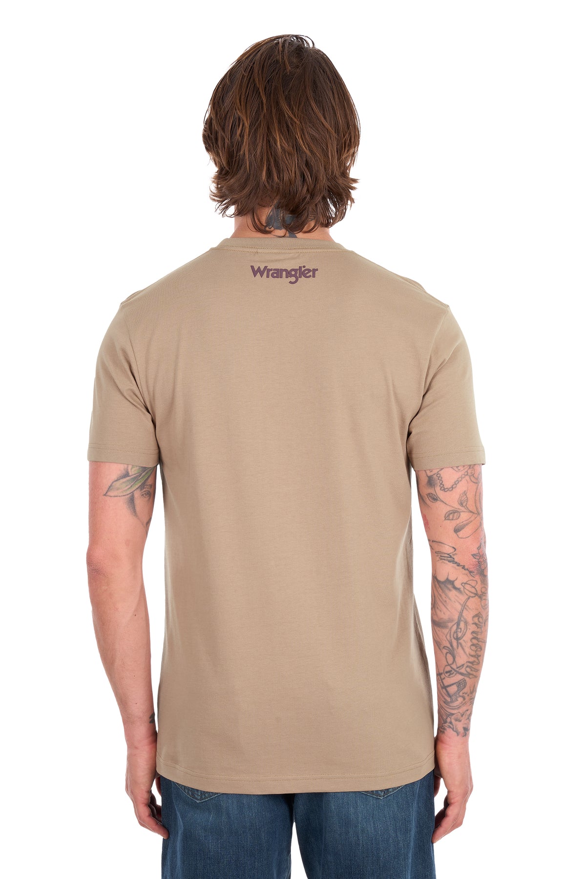 A man viewed from the back wearing a tan short-sleeve crewneck t-shirt with a small purple 'Wrangler' logo printed on the upper back, paired with blue jeans against a white background.
