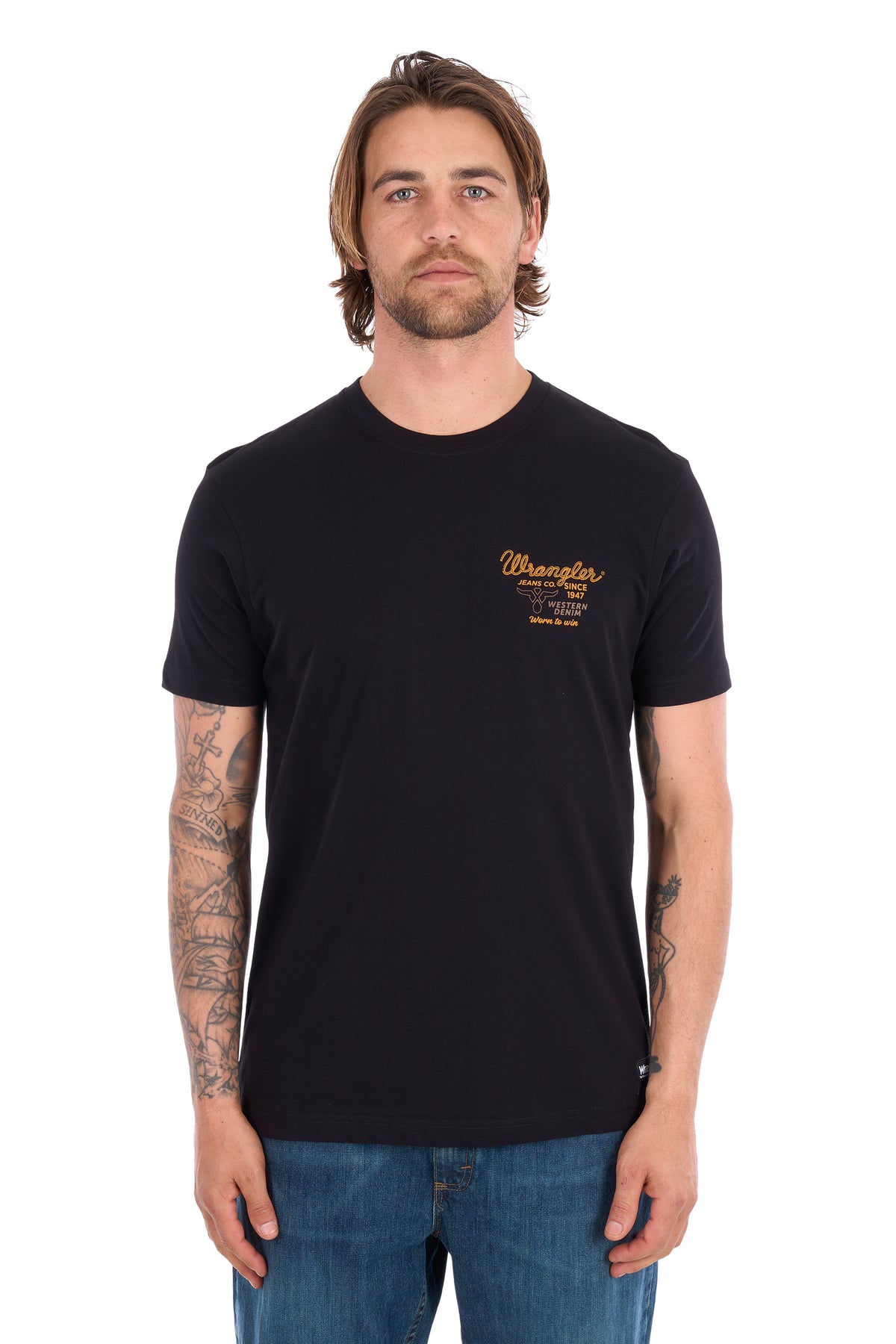 A man wearing a black Wrangler short-sleeve t-shirt with a gold logo on the left chest, paired with blue jeans, photographed against a solid white background.