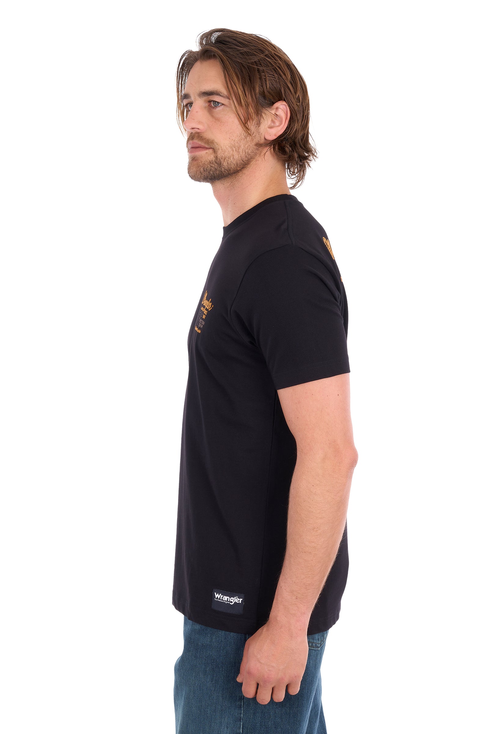 A man shown in profile wearing a black short-sleeve t-shirt with small gold and white graphics, paired with blue jeans, against a plain white background.