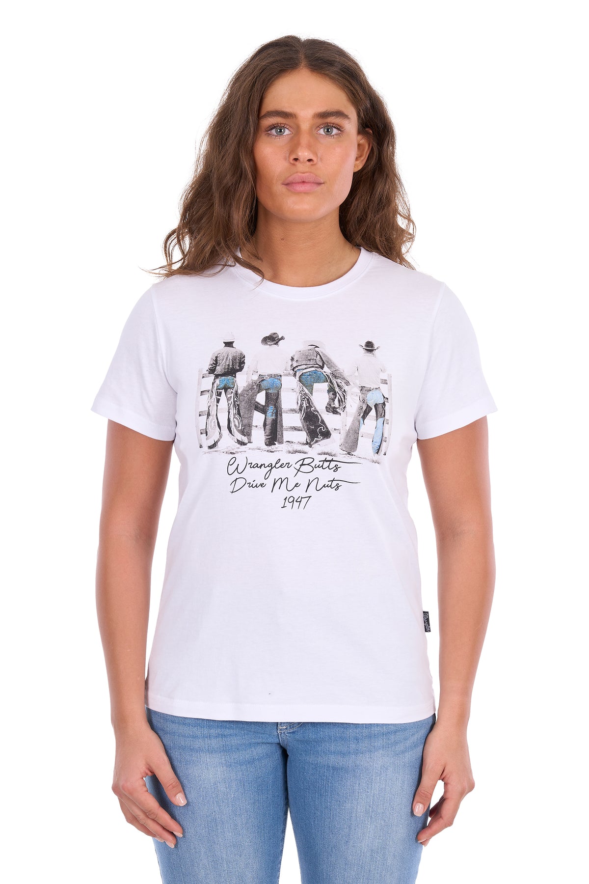 A woman modeling a white graphic t-shirt with a black and blue print of Jim Morrison and the text 'By Your Boots Die My Boots 1977', paired with blue jeans against a plain white background.