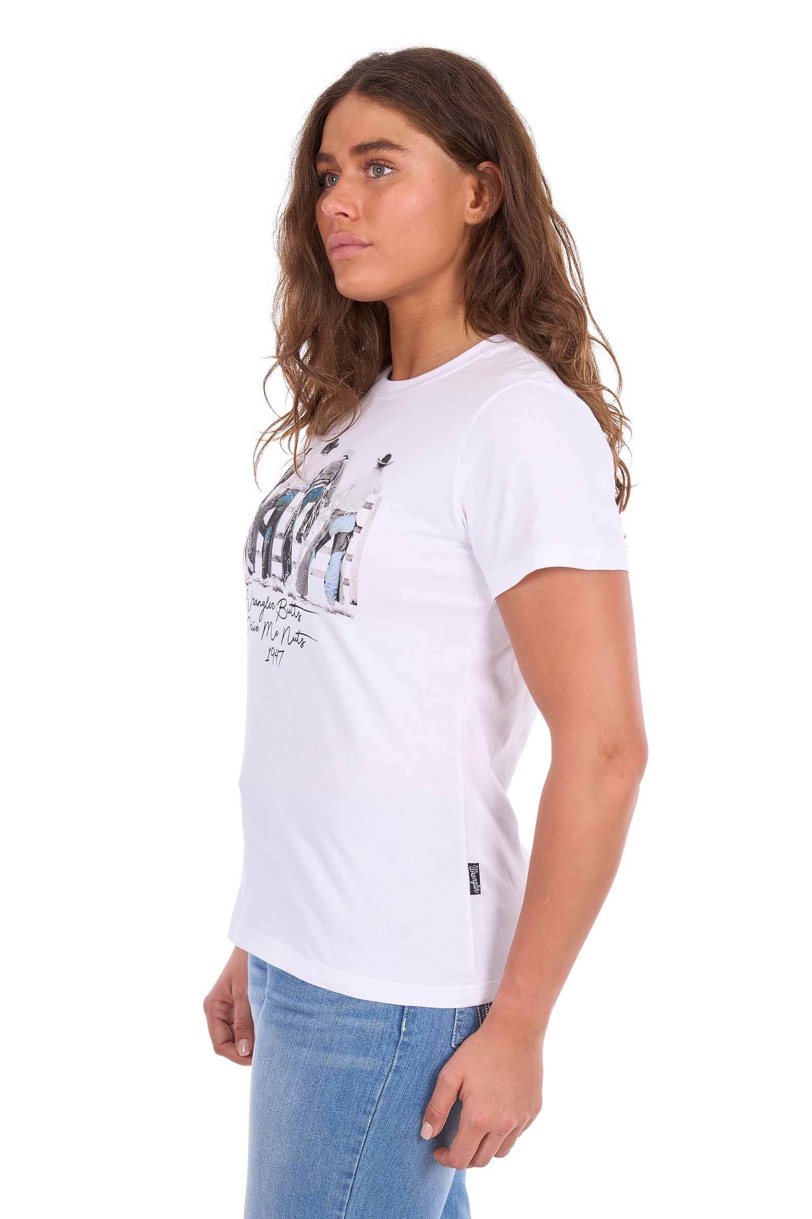 A woman wearing a white short-sleeve graphic t-shirt with a distressed print on the front, paired with light blue jeans, shown from a side profile against a white background.