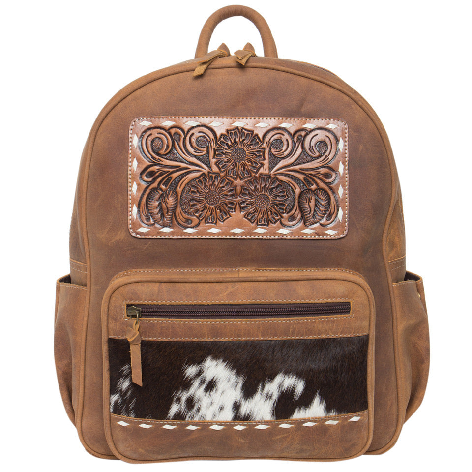 Brown leather backpack with decorative panel and cowhide pattern on a white background