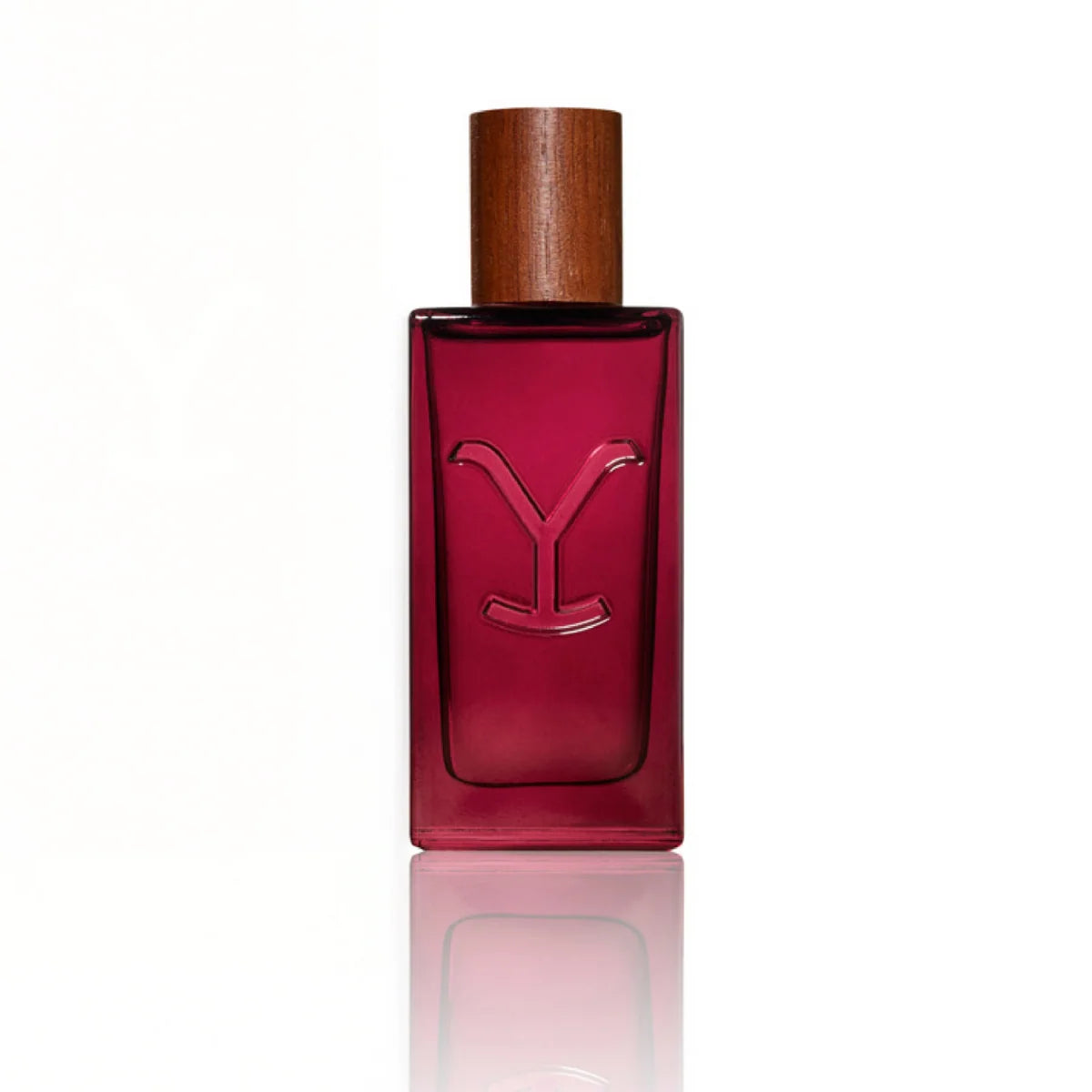 A rectangular glass perfume bottle with a deep magenta-red tint, featuring an embossed stylized 'Y' logo on the front and a cylindrical wooden cap, set against a plain white background with a soft reflection below.
