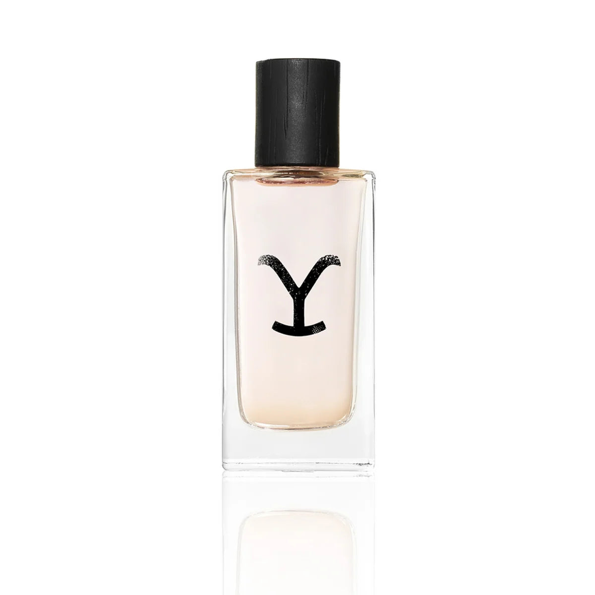 A clear rectangular glass perfume bottle with a black cap and a black stylized 'Y' logo on the front, containing a pale peach-pink liquid, shown on a white background with a soft reflection below.