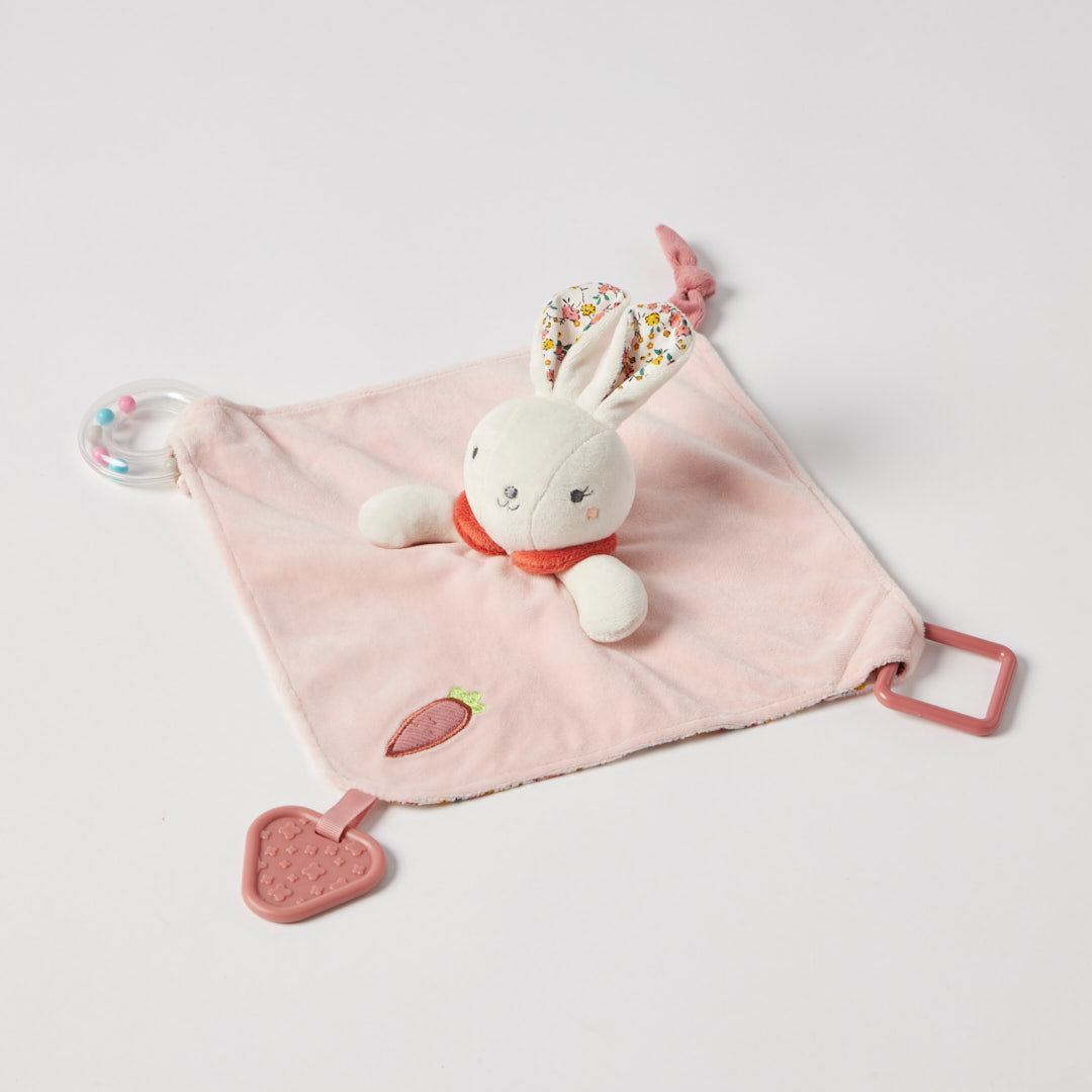 Pink baby comfort blanket with a plush bunny toy on a light gray background
