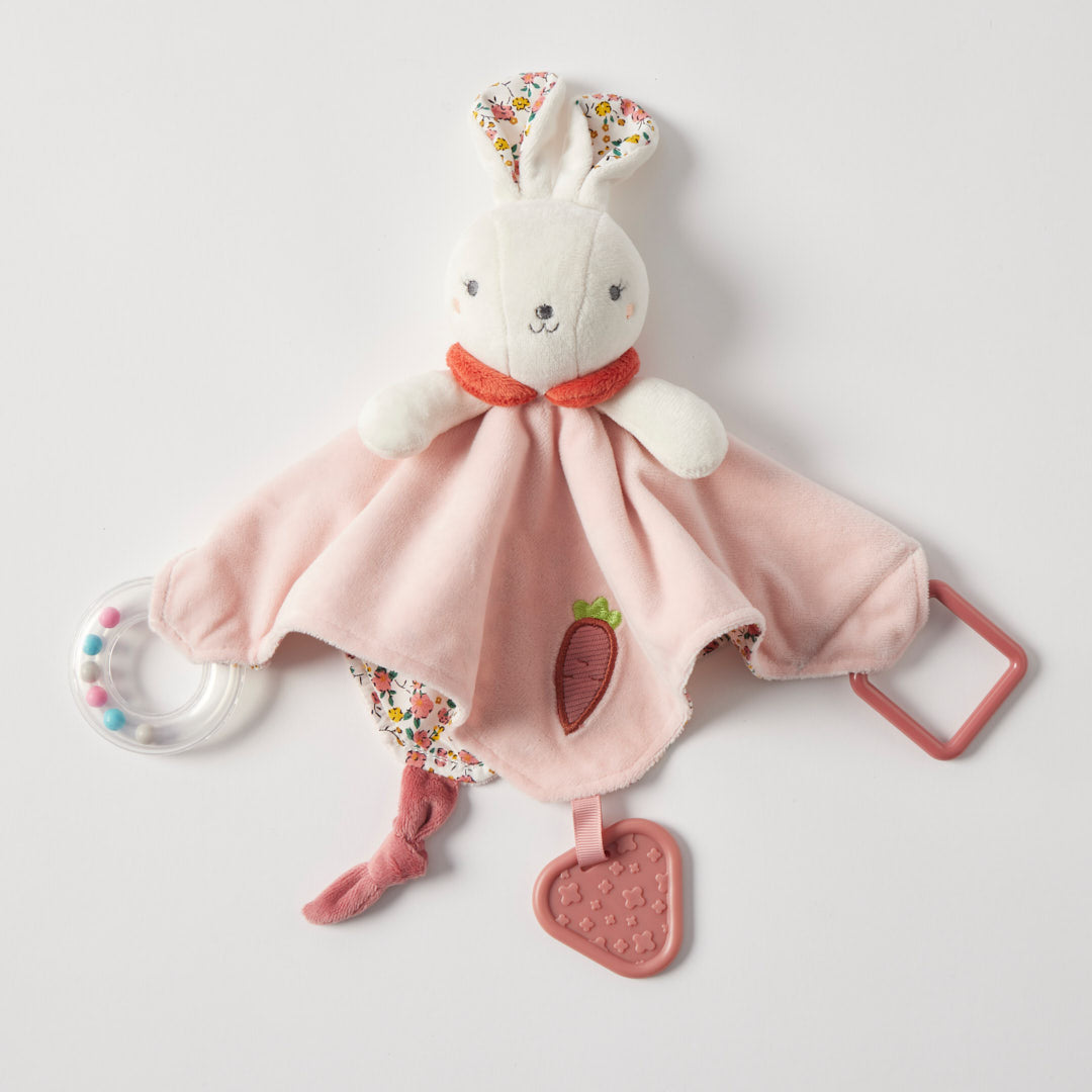 Plush toy with pink blanket and carrot design on a light gray background