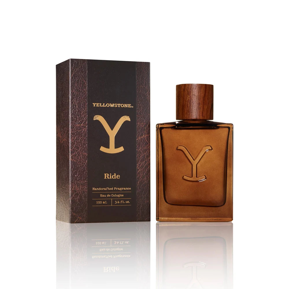 A rectangular amber-brown glass perfume bottle with a matching wooden cap and a large embossed letter Y on the front, centered on a white background with a soft reflection below.