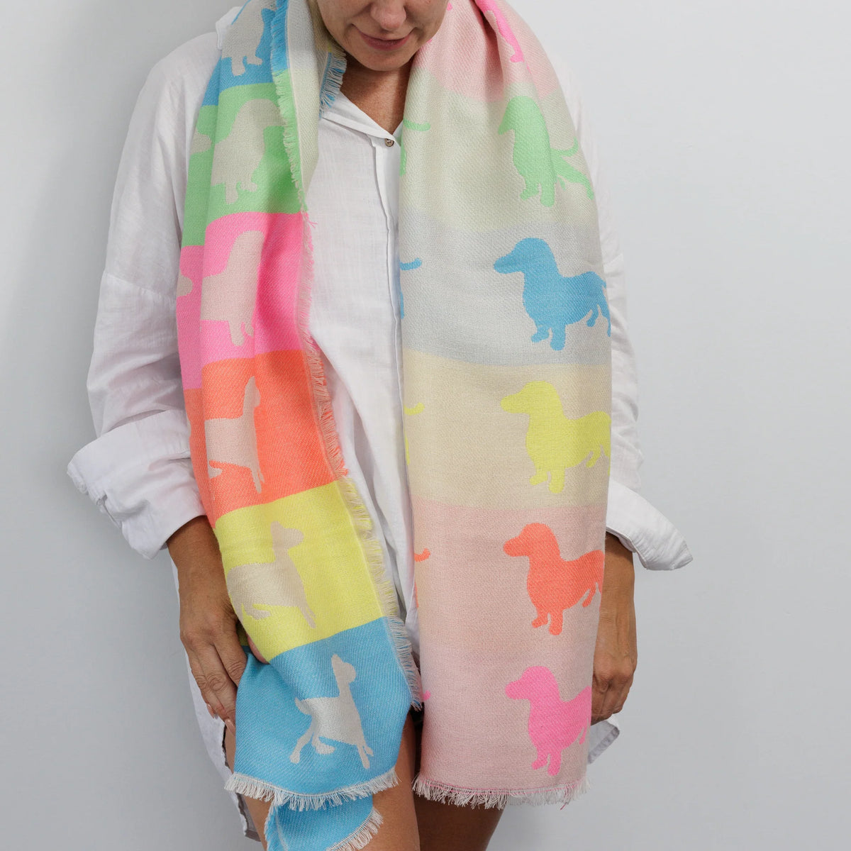 Person wearing a colorful scarf with dog patterns on a plain background