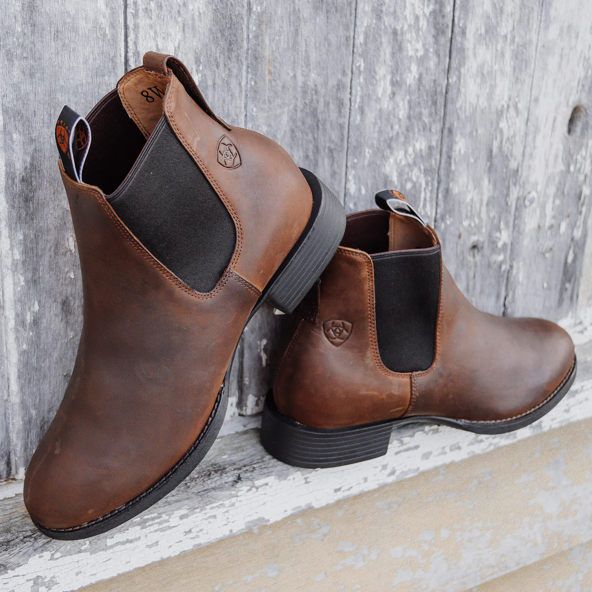Pair of brown leather boots with black soles on a wooden surface