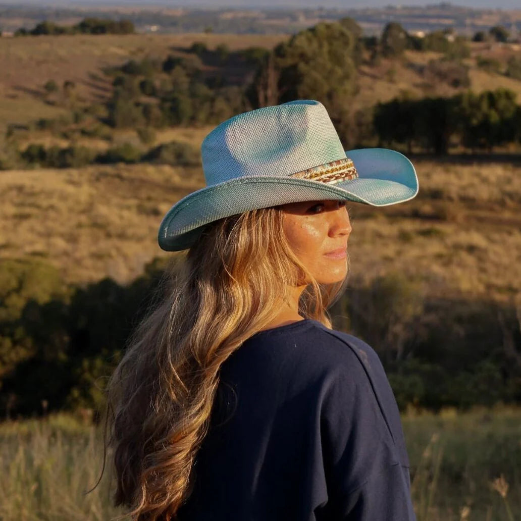 Woman wearing a blue hat in a field with a scenic background