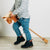 Bigjigs Toys Wooden Hobby Horse. Child holding a toy horse on a light wooden floor with a plain white wall background