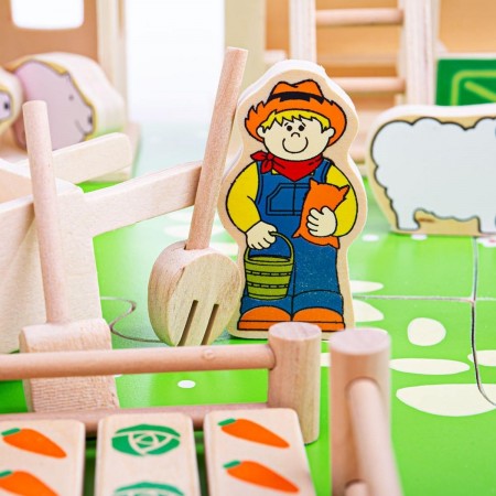 Bigjigs Toys Play Farm. Wooden toy figure of a farmer with a basket, holding a book, on a green play mat with wooden blocks.