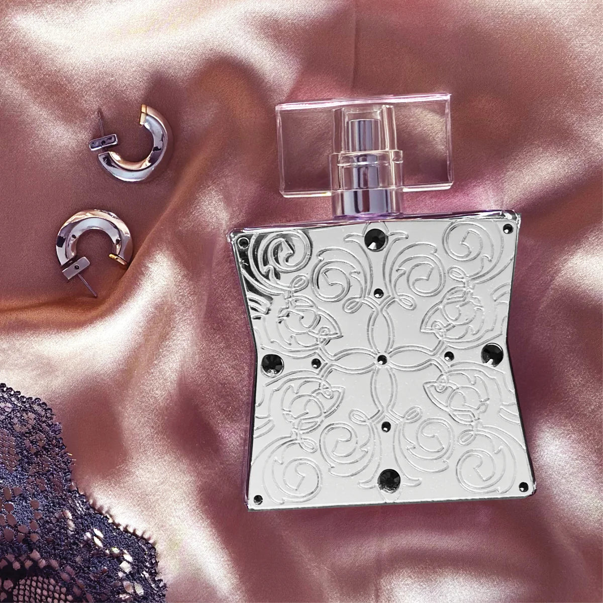 Decorative silver perfume bottle with intricate patterns on a pink fabric background