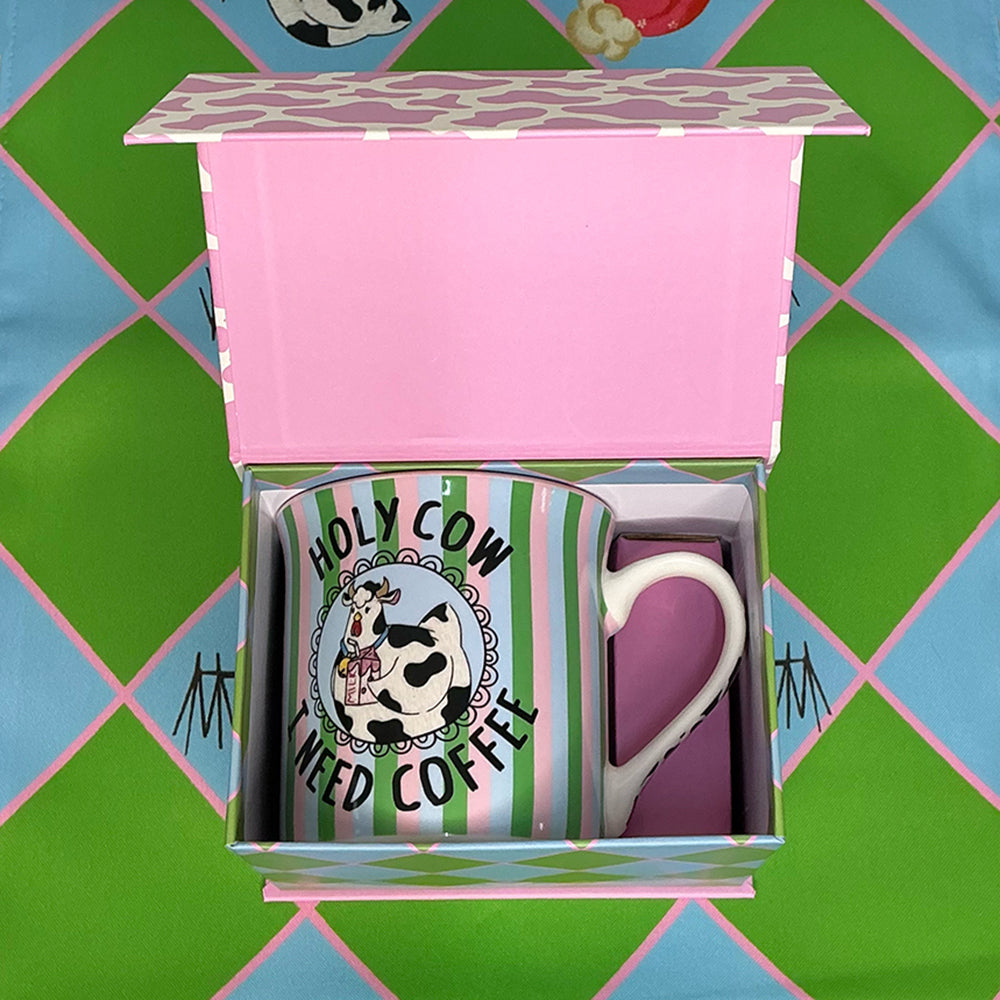 Striped mug with cow design and text in a pink box on a colorful geometric background