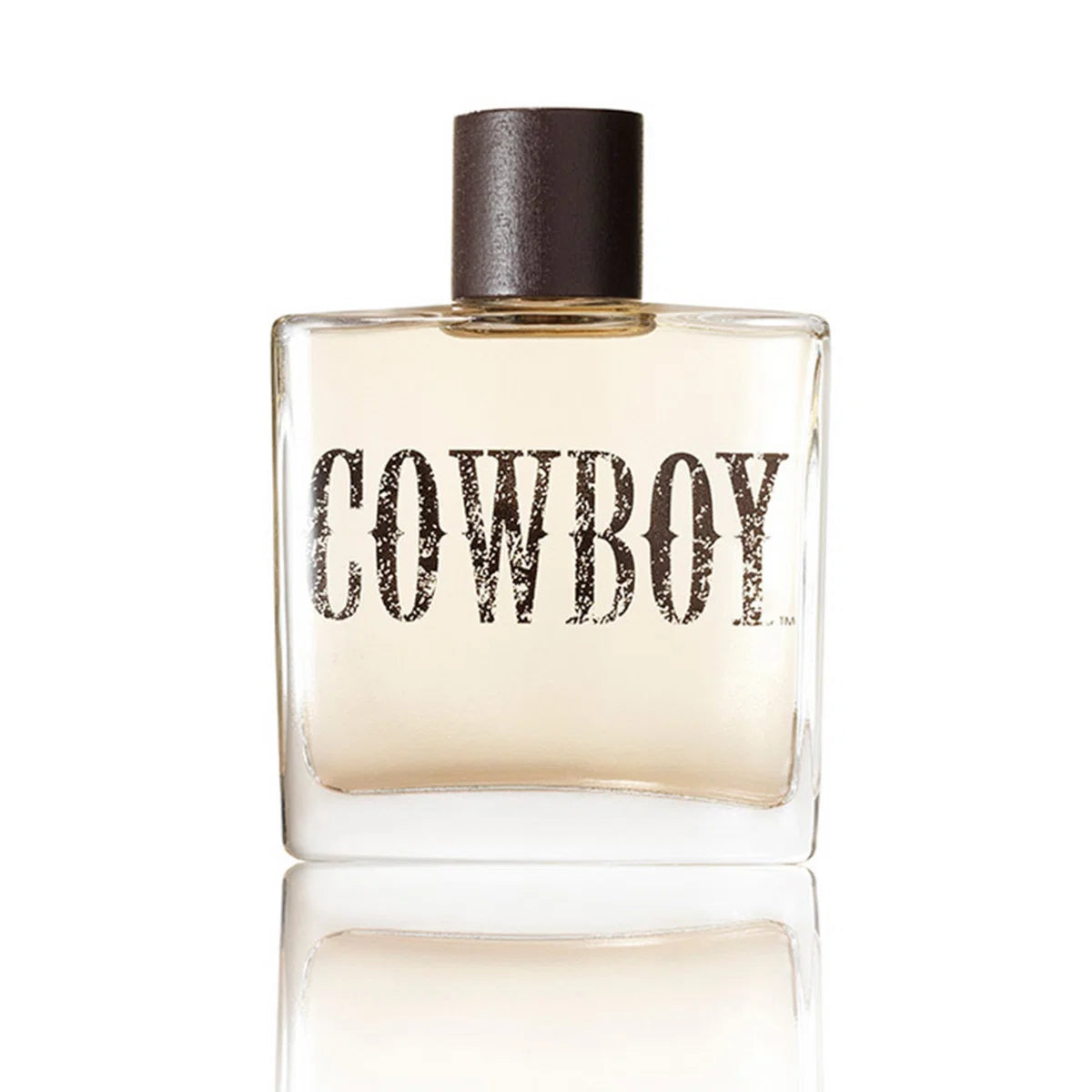 A square glass perfume bottle with a dark brown cap and the word 'COWBOY' printed across the front, shown on a white background with a soft reflection below.