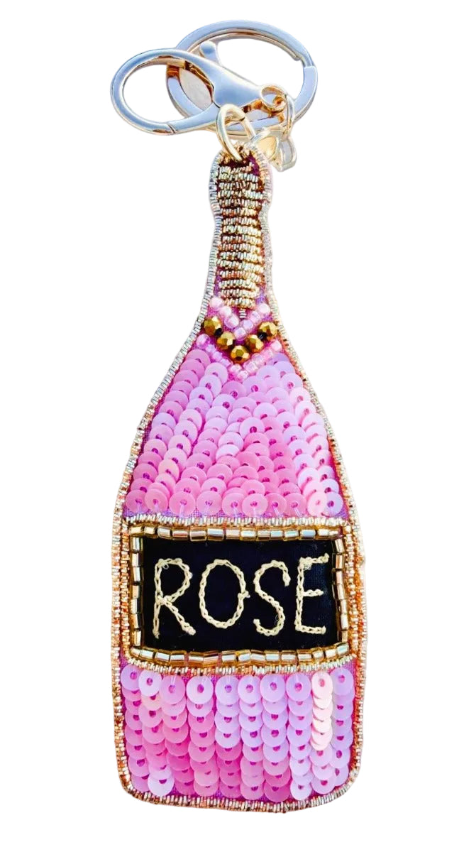 Keychain shaped like a pink bottle labeled 'Rose' on a textured surface.