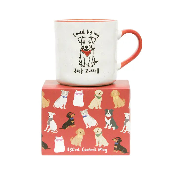 A white ceramic mug with an orange-red handle and interior, printed with a dog illustration and the text 'Loved by my Jack Russell,' displayed on top of a red patterned box.