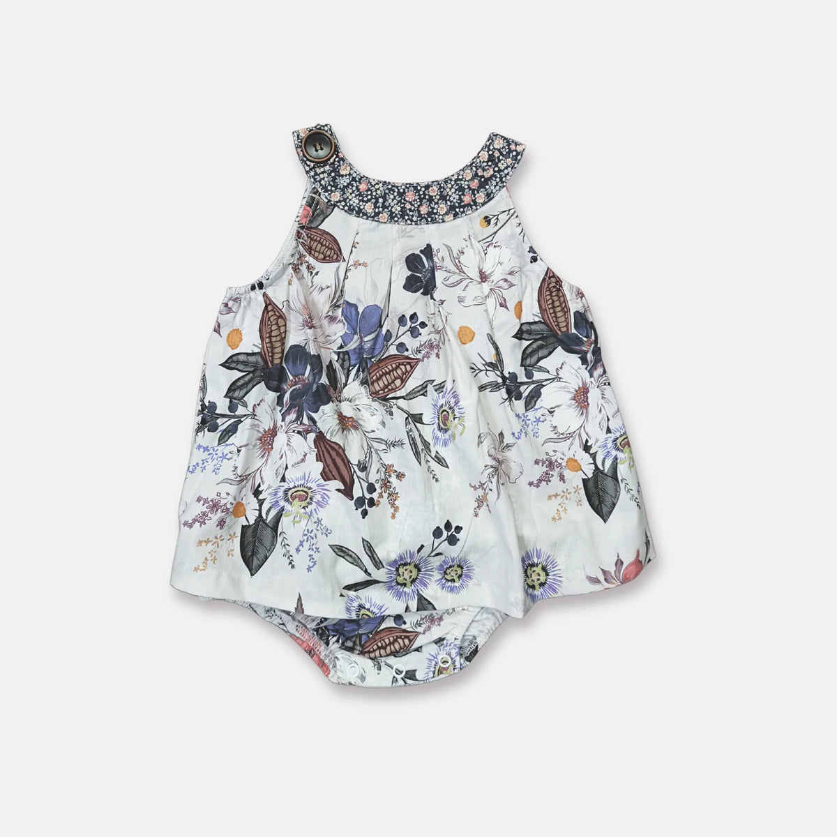 A sleeveless baby romper with a white base and a colorful floral and butterfly print, featuring a patterned fabric collar and shoulder straps.