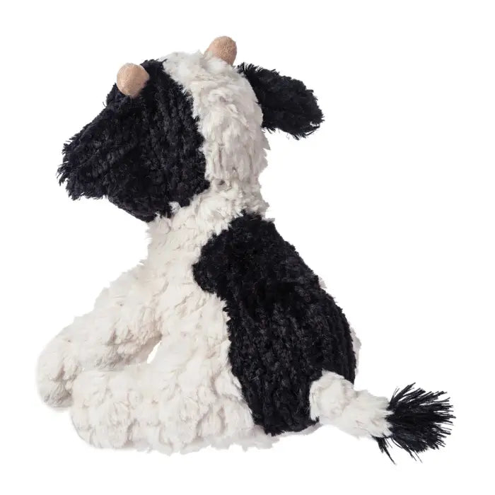 Black and white plush cow toy on a white background