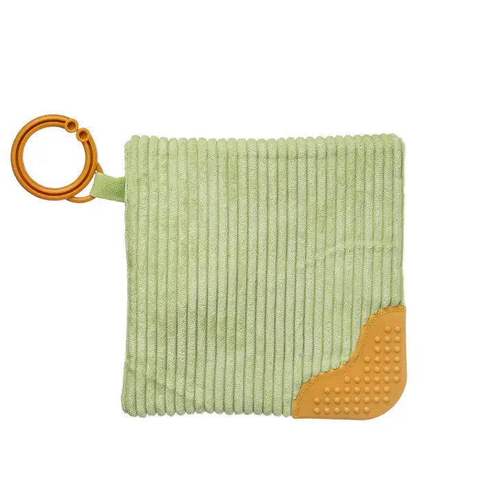 A light green ribbed fabric baby teether or washcloth with a textured orange corner and an orange ring pull, shown on a plain white background.