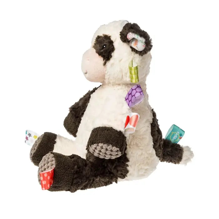 A black and white plush cow toy with textured sensory patches on its hooves, ears, and body, shown against a solid white background.